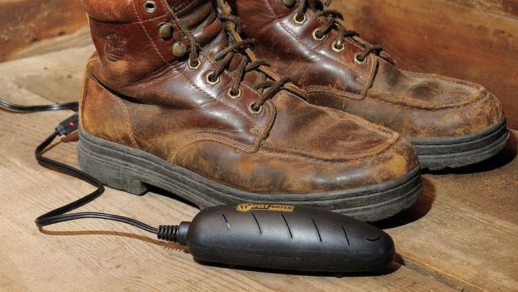 Pair of brown leather boots with a black boot warmer on a wooden floor.